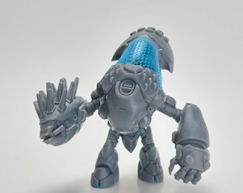 May include: A gray robot action figure with a blue, honeycomb-patterned head. The figure has articulated arms and legs, and a spiky hand. The robot is standing on a white surface.