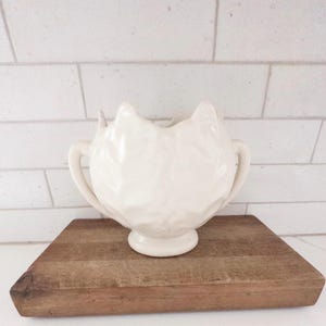 May include: A set of three ceramic mugs with a speckled, matte finish. The mugs are in shades of cream, light gray, and dark gray. Each mug has a simple, minimalist design, perfect for coffee or tea.