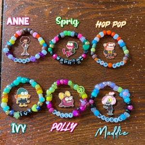 May include: Six colorful beaded bracelets with character charms and names: Anne, Sprig, Hop Pop, Ivy, Polly, and Maddie. Each bracelet features a unique color scheme and character illustration, perfect for fans of the show.