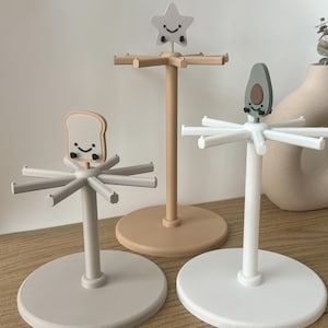 May include: Three decorative countertop organizers with a star, avocado, and slice of bread design. Each organizer has a white, beige, or gray base and a white, beige, or gray stand with eight arms.