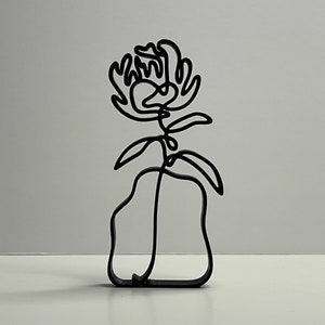 May include: A black metal sculpture of a flower in a vase. The flower is stylized and has a simple, modern design.