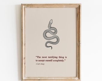 May include: A black and white illustration of a snake with the quote "The most terrifying thing is to accept oneself completely." -Carl Jung. The quote is printed on a beige background and framed in a light wood frame. The text "Brush Chérie" is printed in red at the bottom of the image.