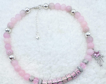 May include: A pink beaded necklace with silver accents and a star charm. The necklace features pink beads, silver beads, and lettered cubes spelling "SEONGHA". A star charm with a pink gem and silver accents hangs from the necklace.