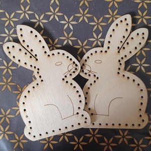 May include: Two unfinished wooden bunny shapes with holes for stringing. The bunnies are facing each other and have a simple design.