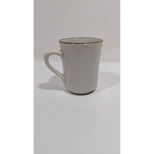 May include: A speckled, off-white ceramic mug with a brown rim and handle. The mug has a simple, classic design, suitable for coffee or tea. The mug is approximately 4 inches tall.