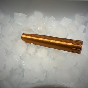 K&ouml;nnte beinhalten: Ein kupferfarbenes Metallrohr liegt auf einem Bett aus Eisw&uuml;rfeln in einem wei&szlig;en Plastikbeh&auml;lter.
