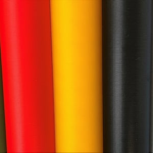 K&ouml;nnte beinhalten: Nahaufnahme von acht verschiedenen farbigen Filamentrollen f&uuml;r einen 3D-Drucker. Die Farben sind blau, gr&uuml;n, rot, orange, gelb, schwarz, wei&szlig; und kupfer.