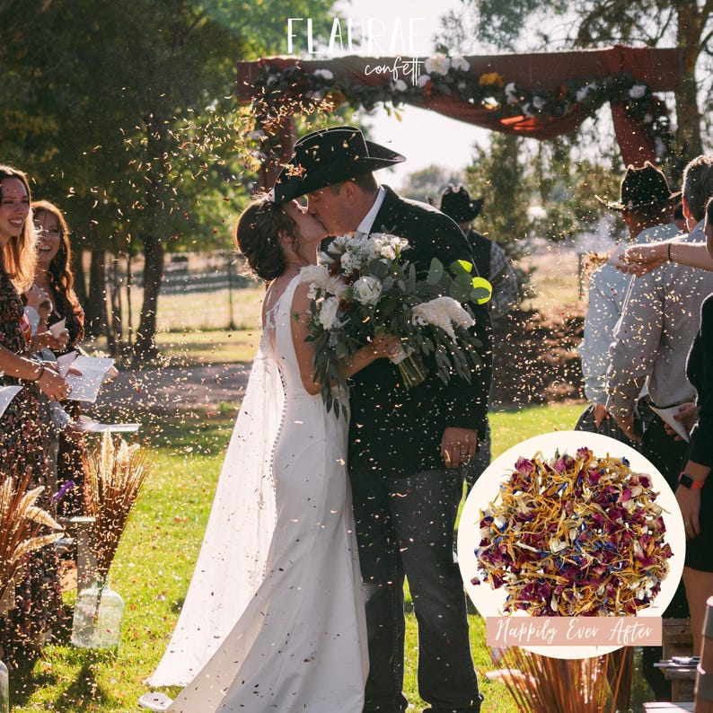 May include: A wedding scene with a bride and groom kissing under a wooden arch decorated with flowers. Confetti is being thrown in the air. A bouquet of white and red flowers is held by the groom. A circular image of dried flower confetti is in the foreground.