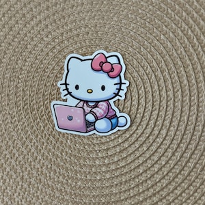 May include: A white Hello Kitty character wearing a pink sweater and a pink bow is sitting on a laptop computer. The laptop is pink and has a heart on the screen.