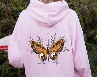 May include: Pink hoodie with a butterfly graphic on the back. The butterfly has the words "Free Spirit" written on its wings and a yin yang symbol on each side.