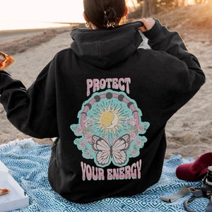 May include: Black hooded sweatshirt with a graphic print of a butterfly, sun, moon, and the text "Protect Your Energy".