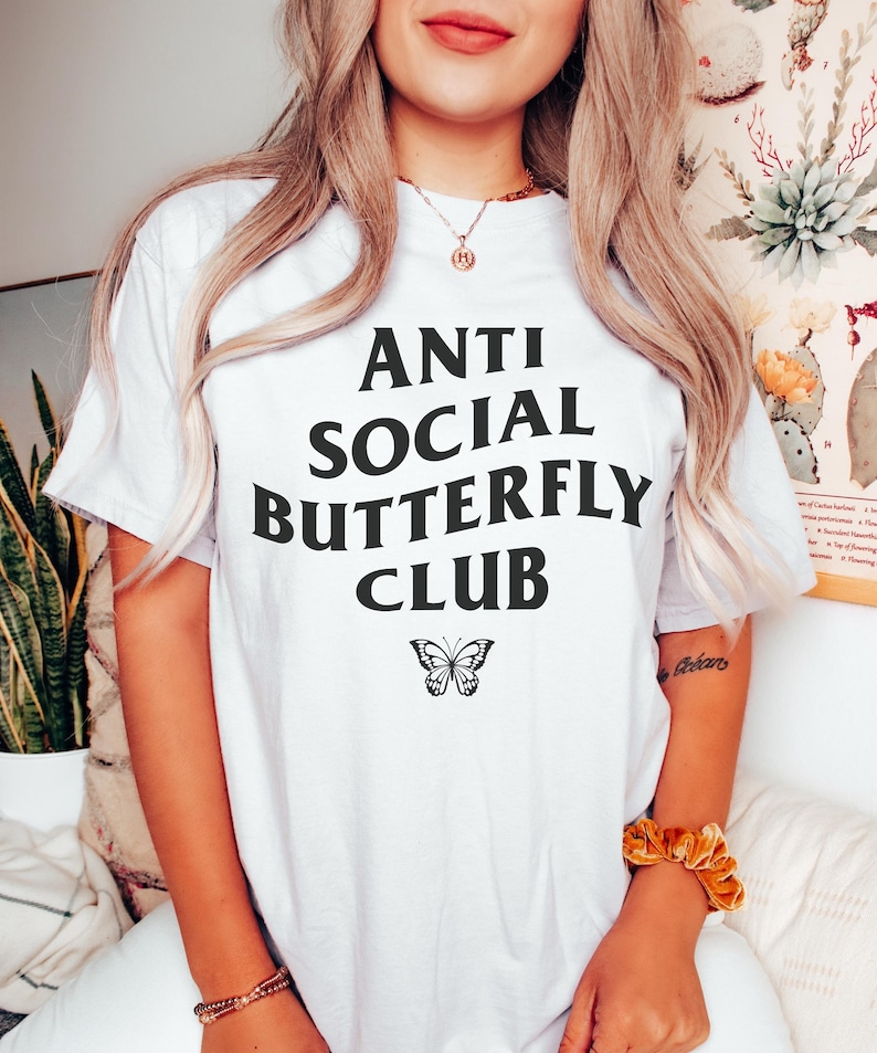 May include: White t-shirt with black text that reads "Anti Social Butterfly Club" and a black butterfly graphic.