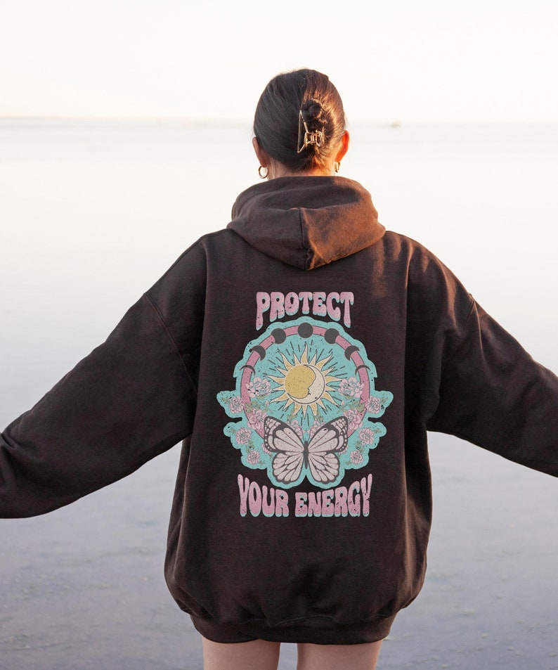 May include: A brown hoodie with a graphic print on the back. The graphic features a sun, moon, and butterfly with the text "Protect Your Energy".