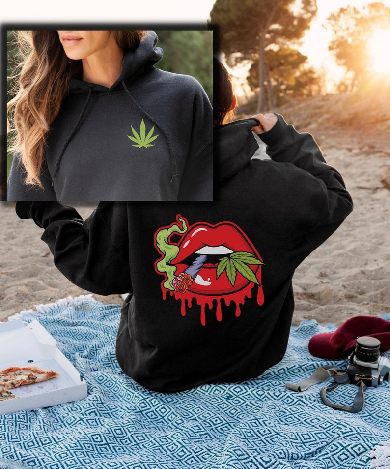 May include: Black hoodie with a green cannabis leaf on the front and a red dripping mouth with a cannabis leaf and a joint on the back.