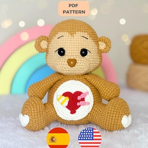 May include: A tan crochet monkey plush toy featuring a white circular belly patch with a red heart, a yellow bandage, and pink stitches. The monkey has dark eyes, a brown nose, and white heart-shaped patches on its feet. Text reads PDF PATTERN.