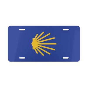 May include: A blue and gold license plate featuring the scallop shell, a symbol of the Camino de Santiago pilgrimage route.