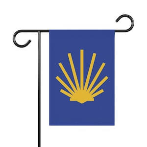 May include: A blue garden flag featuring a yellow scallop shell design. The flag is mounted on a black metal stand with a curved top. The shell design has a sunburst pattern.