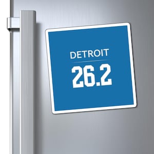 Puede incluir: Un imán cuadrado azul con texto blanco que dice "DETROIT 26.2".