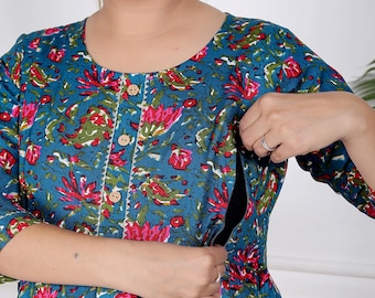 Könnte beinhalten: Türkisfarbenes Kleid mit floralem Muster, Rundhalsausschnitt und Dreiviertelärmeln. Das Kleid hat eine Knopfleiste vorne und eine geraffte Taille. Das Blumenmuster enthält rote und grüne Akzente. Das Kleid scheint zum Stillen entworfen zu sein.