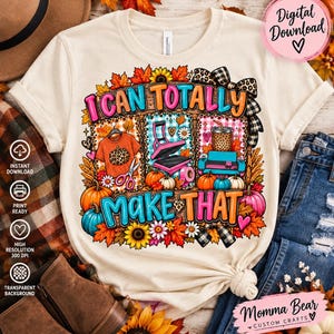 Könnte beinhalten: Ein cremefarbenes T-Shirt mit einem Grafikdesign und dem Text I CAN TOTALLY MAKE THAT. Die Illustration zeigt ein T-Shirt, eine Heißpresse, einen Becher, eine Schere, Kürbisse, Sonnenblumen und herbstliche Blätter in leuchtenden Farben.