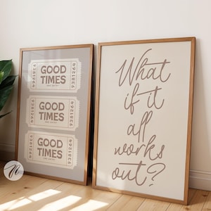 以下が含まれることがあります： 2つの額入りアートプリント。1つは「Good Times」のチケット3枚。もう1つは筆記体で「What if it all works out?」と書かれています。どちらも木製のフレームで、ニュートラルな背景とくすんだ茶色のテキストです。