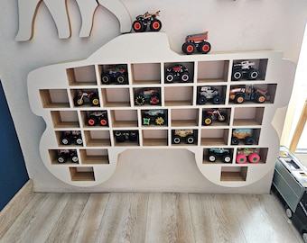 May include: White wooden monster truck shelf with multiple shelves for toy trucks. The shelves are filled with various toy monster trucks in different colors and designs.