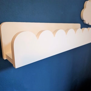 May include: White wooden shelf with a scalloped edge, mounted on a blue wall.