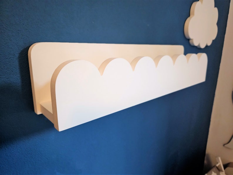 May include: White wooden shelf with a scalloped edge, mounted on a blue wall.