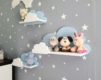 May include: Three white cloud-shaped shelves with blue accents are mounted on a gray wall. The shelves are decorated with stuffed animals, including a giraffe, a cat, a dog, and a rabbit.