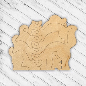May include: A wooden cutout of a stack of cats, each cat is in a different pose. The cats are all facing the same direction. The cutout is made of light brown wood and has a smooth finish.