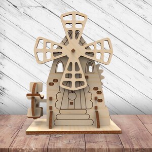 May include: A wooden windmill model with a detailed design. The windmill has a rotating blade and a small door with a window. The model is made of light brown wood and has a rustic charm.