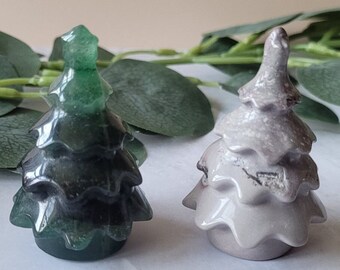 May include: Two small, hand-carved, crystal Christmas tree ornaments. One is green and the other is gray.