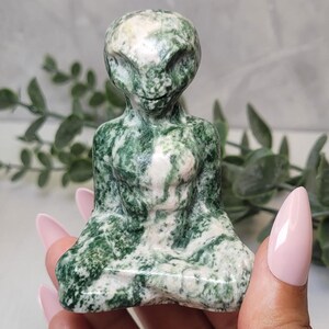 May include: Green and white marbled stone sculpture of a seated alien figure.