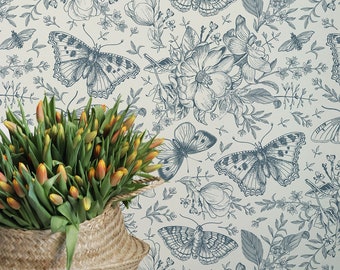 May include: A white chair with wooden legs and a woven basket filled with yellow tulips sits in front of a wall covered in a blue and white floral wallpaper with a butterfly pattern.