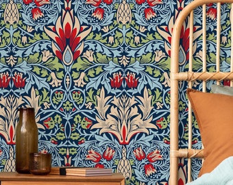 May include: A bedroom interior with a patterned wallpaper featuring a blue, green, red, and cream floral design. A wooden nightstand with a drawer sits in front of the wallpaper. A bed with a brown and white knitted blanket is in the background.