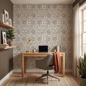 Pu&ograve; includere: Uno spazio ufficio domestico con carta da parati caratterizzata da un motivo astratto a linee topografiche nere e beige. La stanza include una scrivania in legno chiaro, una sedia girevole grigia con una coperta color ruggine e mensole.