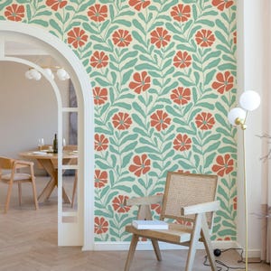 Puede incluir: Un papel tapiz con un patrón repetitivo de flores naranjas y hojas verdes sobre un fondo crema. El papel tapiz se muestra en una habitación con una silla y una lámpara.