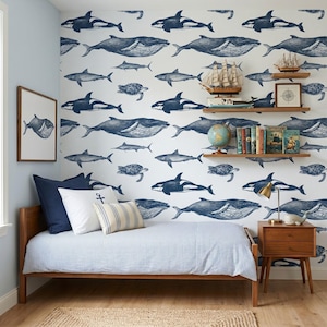 May include: A bedroom featuring wallpaper with a dark blue nautical pattern of whales, sharks, and sea turtles. The room includes a wooden bed frame with blue and white striped bedding, a wooden nightstand, and two wall shelves holding books and decor.