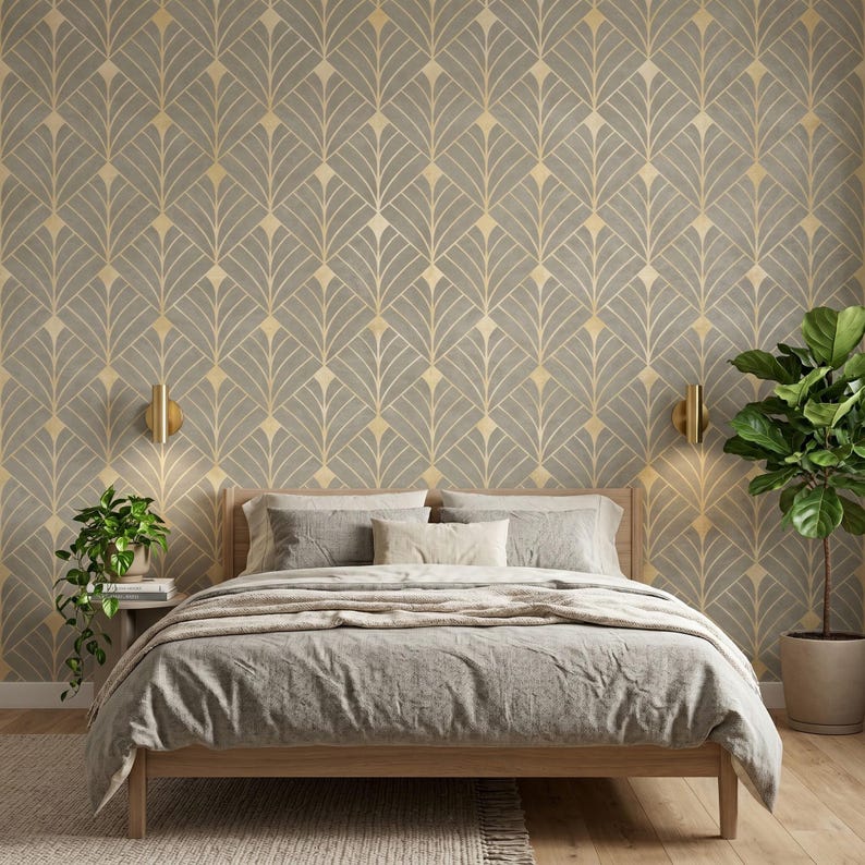 May include: A bedroom featuring wallpaper with a repeating gray and gold fan-shaped geometric pattern. The room includes a wooden bed frame with gray bedding, two wall-mounted gold sconces, and two potted green plants on either side.