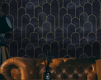 May include: A dark brown leather sofa with button tufting sits in front of a wall with a geometric pattern of gold arches on a dark blue background. A black diffuser bottle with black reeds sits on a wooden table in front of the sofa.