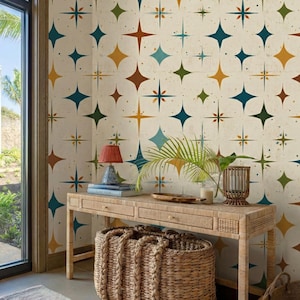 Puede incluir: Interior con diseño retro. Una consola de mimbre de color claro y una cesta a juego son el punto focal. La pared presenta un papel pintado de estrellas en tonos turquesa, marrón y dorado. Una pequeña lámpara y objetos decorativos están sobre la mesa.