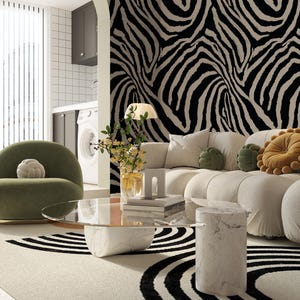 May include: A modern living room with a white sofa, olive green chair, and a marble coffee table. The room features a black and white zebra print accent wall and a patterned rug. Decorative pillows in green and gold add pops of color.
