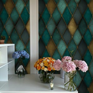 May include: A white desk with three vases of flowers. The flowers are blue, orange, and pink. The background is a teal and gold diamond pattern wallpaper. A small candle is on the desk.