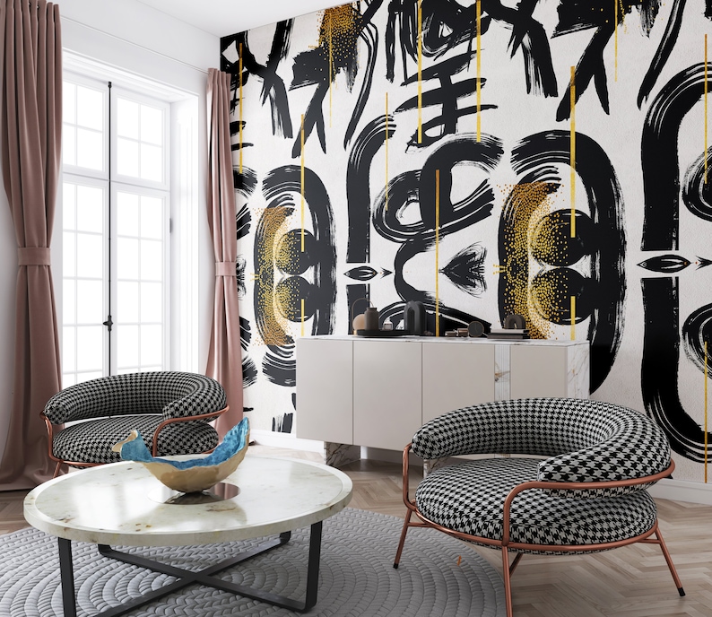 May include: A living room interior with a white wall featuring a black and gold abstract art print. Two black and white checkered chairs are placed in front of a white coffee table with a blue and gold decorative bowl.