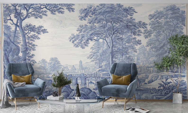 Puede incluir: Un interior de sala de estar con dos sillones azules y una mesa de caf&eacute;. La pared est&aacute; decorada con un papel tapiz azul y blanco que representa un paisaje con &aacute;rboles, un puente y una ciudad en la distancia.