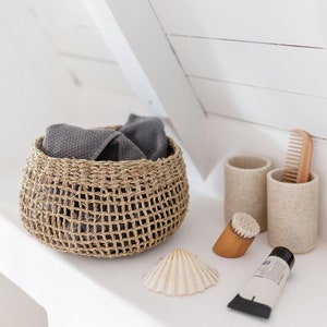 Runder Seegras Korb Bola im Badezimmer, gefüllt mit einem Handtuch, neben Waschbecken platziert