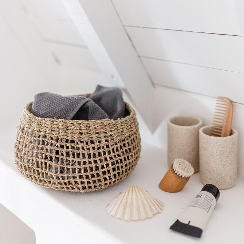 Runder Seegras Korb Bola im Badezimmer, gefüllt mit einem Handtuch, neben Waschbecken platziert