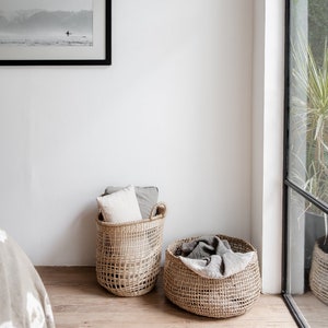 Seegras Korb Bola neben einem weiteren Naturkorb, gefüllt mit einer Decke – dekorative und praktische Aufbewahrung im Wohnzimmer