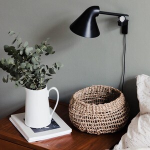 Kleiner Seegras Korb Bola auf dem Nachttisch, dekorativ arrangiert mit minimalistischer Deko im Schlafzimmer