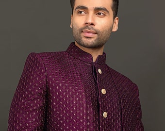Puede incluir: Chaqueta formal de color púrpura oscuro con cuello alto y botones dorados. La chaqueta tiene un patrón texturizado con pequeños detalles dorados. Adecuada para ocasiones especiales.